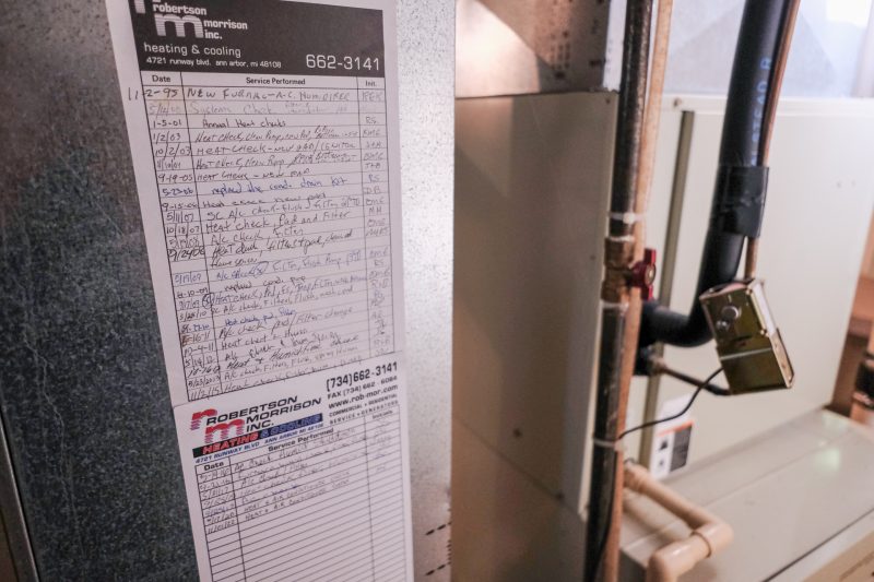 A carefully detailed log on a list on the side of a furnace.