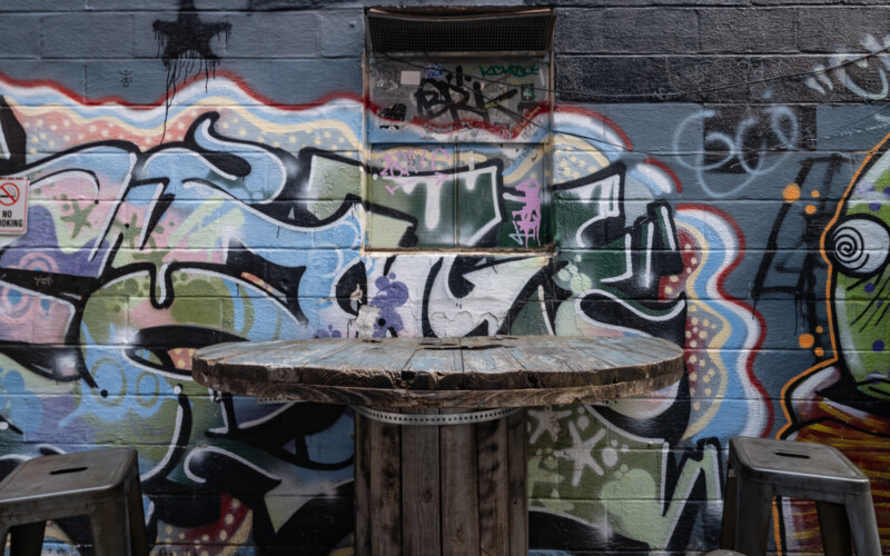 Mural surrounds the outdoor seating at the 8 Ball Saloon. 8 Ball Saloon outdoor seating made from upcycled industrial equipment surrounded by mural.