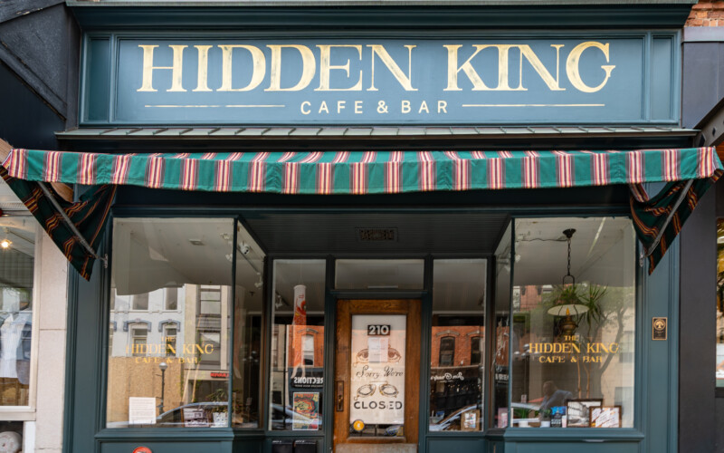 The Hidden King Cafe and Bar in Ann Arbor, Michigan. Hidden King Cafe and Bar is a green storefront with a striped awning.