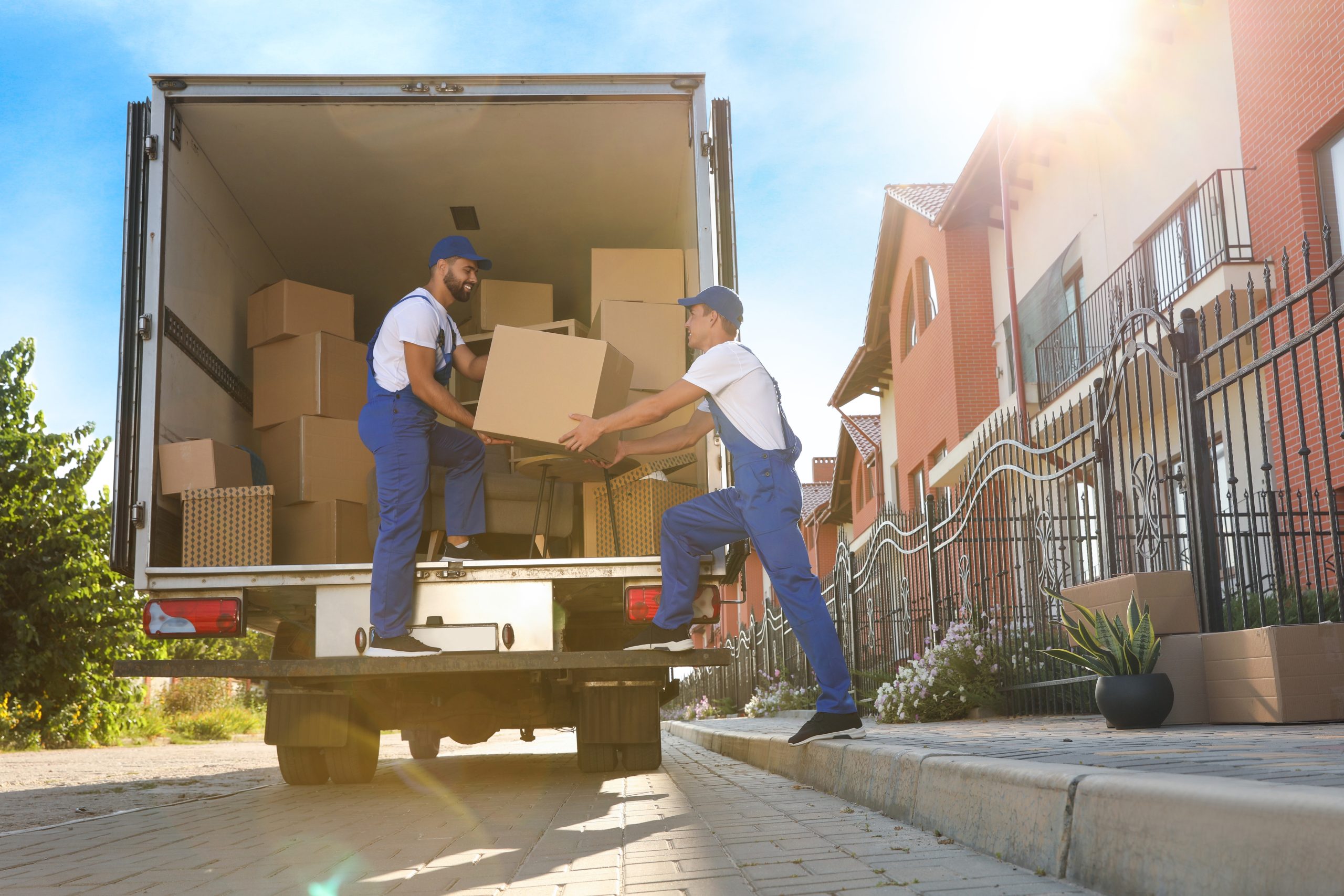 two male movers move boxes into a moving trucks.