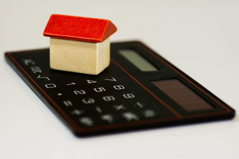 A small wooden house toy on a calculator.